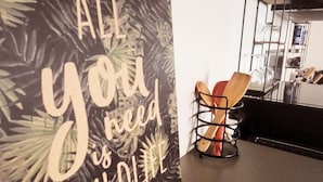 A kitchen with a large decorative sign on the wall, a metal rack with utensils, and a modern shelving unit. - Furnished stopover (Belfort)