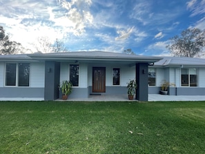 A modern two-story house with a front porch, large windows, and a well-maintained lawn. - Relaxing Acreage Retreat – Pool, Spa & Media Room (Karalee)