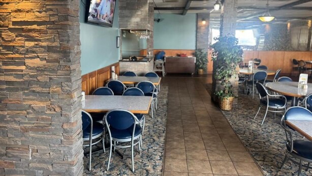 Un restaurante con paredes de piedra, sillas azules y suelo de baldosas.