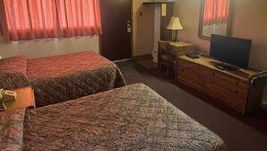 Habitación de hotel con dos camas, un aparador, un televisor y una lámpara.