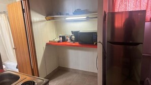 Una cocina compacta con estufa, microondas y refrigerador.