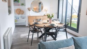 Un comedor con una mesa redonda, sillas negras, un aparador de madera y un ventanal grande.