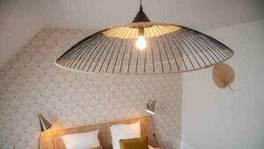Un dormitorio con cama, lámpara colgante y pared con diseño.