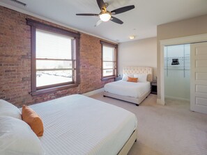 Un dormitorio con dos camas, un ventilador de techo y vistas al exterior a través de amplios ventanales.