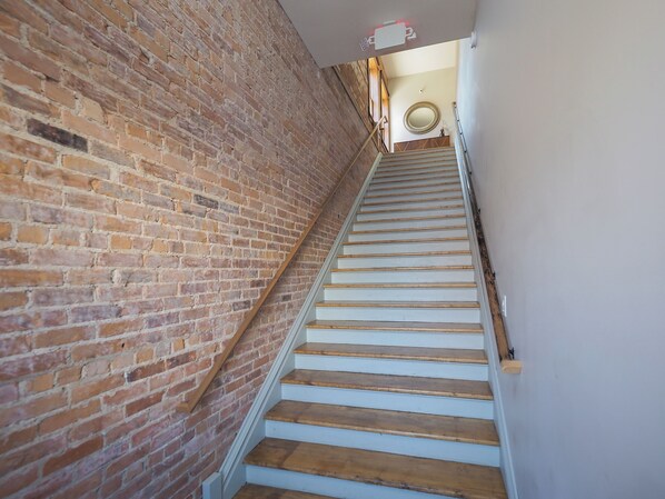 A staircase with wooden steps and a brick wall. - Dreamy Downtown Industrial Luxury Loft (Kalamazoo)