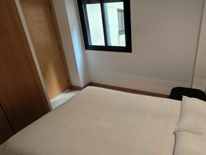 Una habitación con una cama, una ventana y una puerta.