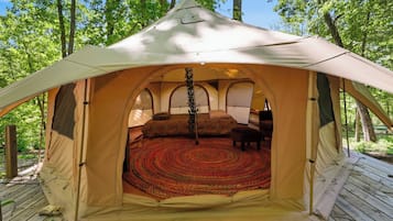 A tent with a circular interior, a central pole, and a patterned floor.