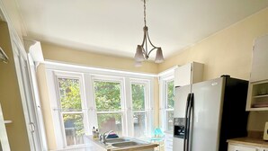 Una cocina con isla central, refrigerador, pileta y ventana con vista a follaje.