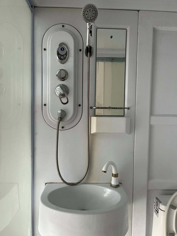 A compact bathroom with a white sink, a handheld showerhead, and a small mirror. - WJV Inn Tejero (Cebu City)