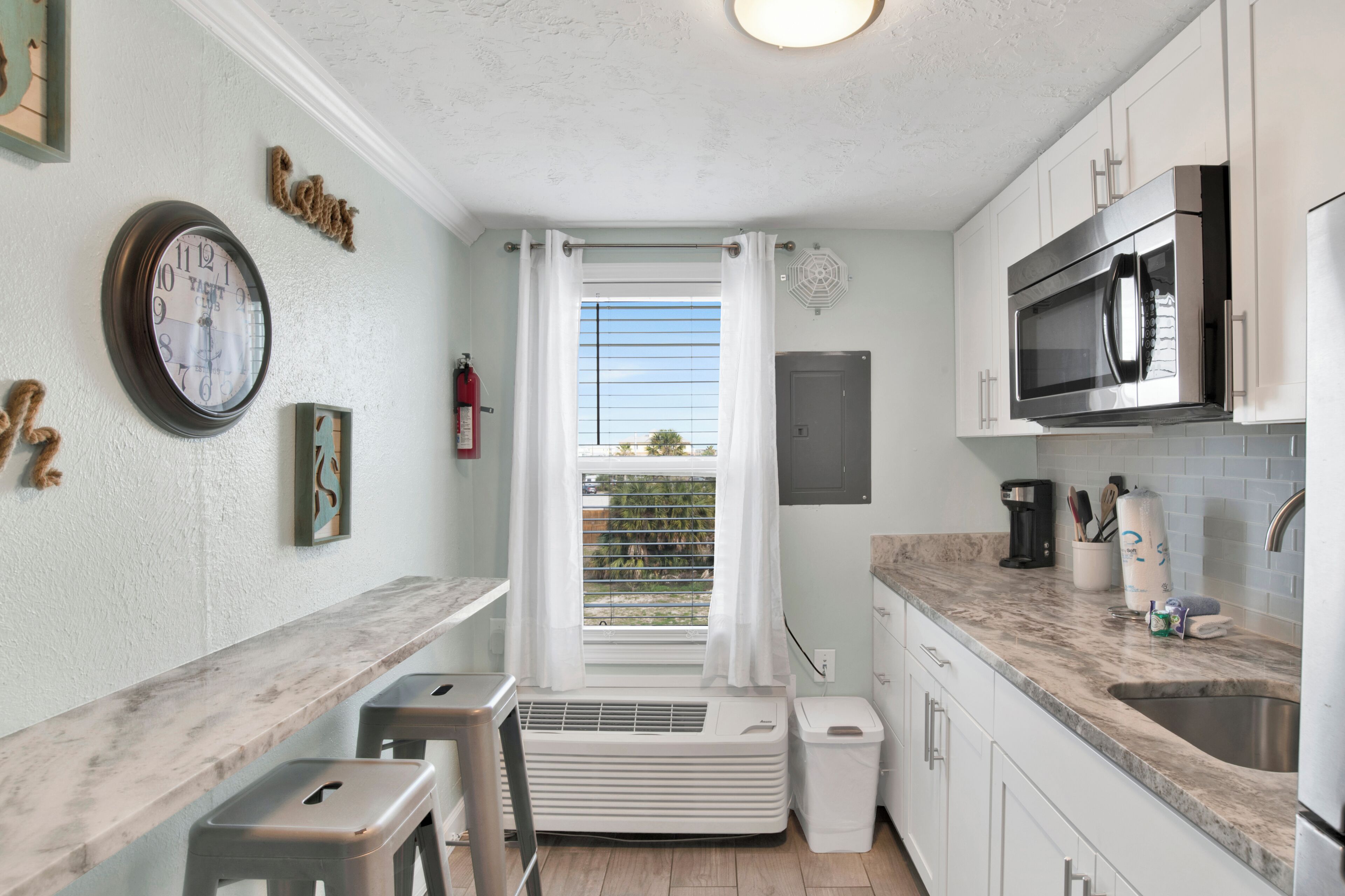 A compact kitchen with a built-in microwave, a coffee maker, and a sink.