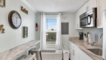 A compact kitchen with a built-in microwave, a coffee maker, and a sink.