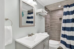 A modern bathroom with a white sink, a mirror, a towel rack, and a shower with a striped curtain. - Steps to Beach & The Hangout • Walk Everywhere • Covered Parking (Orange Beach)