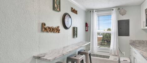 A kitchen with a marble countertop, a clock, and a fire extinguisher.