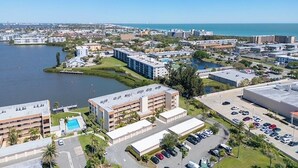 Oversigtsbillede af et kystnært byområde med lystbådehavn, flere højhuse og en parkeringsplads.