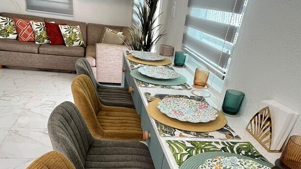 A modern dining area with a long table, multiple chairs, and decorative plates. - Vieques Beach Home, Boho style, within walking distance to beach and a King Bed (Florida)