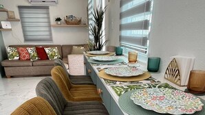 A modern kitchen with a central island, bar stools, and a dining area with a sofa. - Vieques Beach Home, Boho style, within walking distance to beach and a King Bed (Florida)