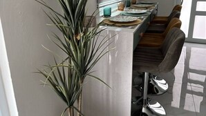 A modern kitchen with a marble countertop, a potted plant, and a dining area with bar stools. - Vieques Beach Home, Boho style, within walking distance to beach and a King Bed (Florida)