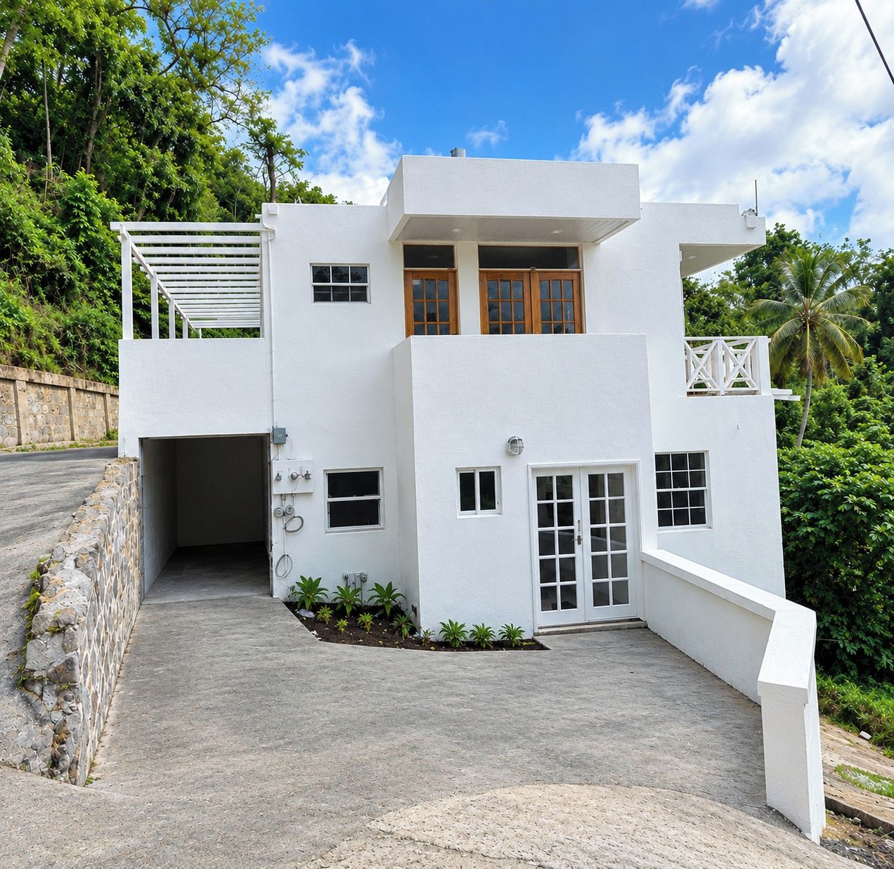 A modern two-story building with a white exterior, a covered entrance, and a small garden area.