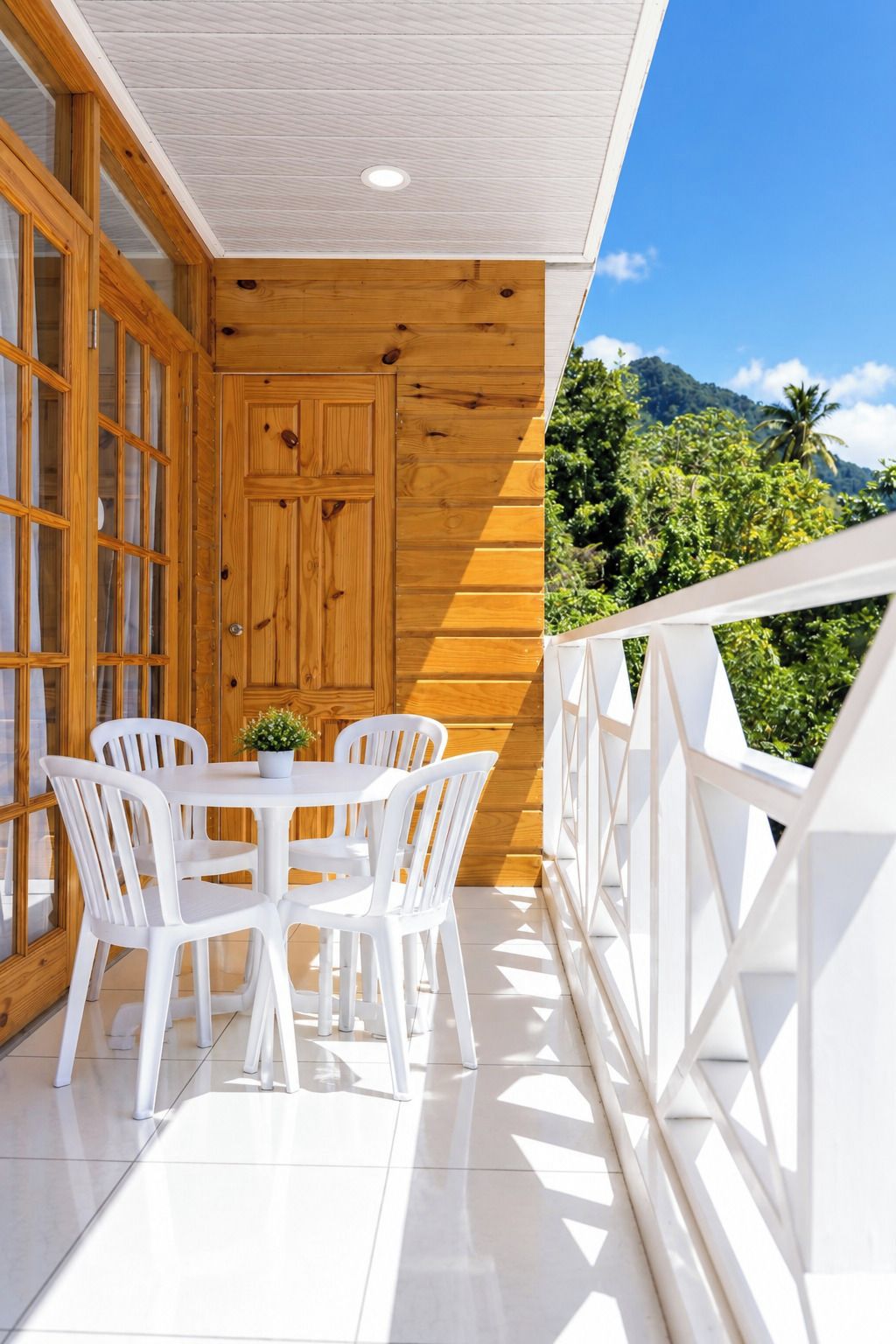 A balcony with a white railing, a wooden door, and a table with white chairs.
