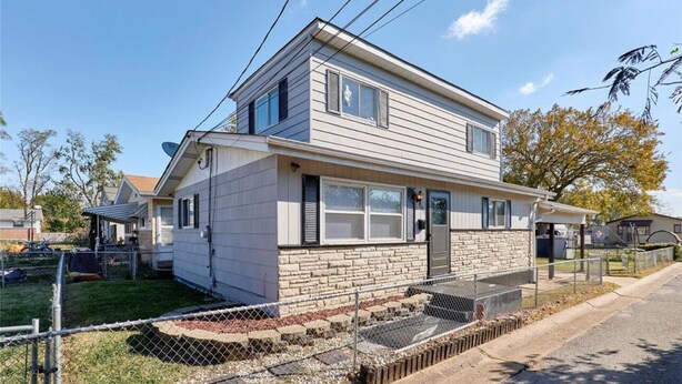 A two-story house with a stone foundation, a front porch, and a fenced yard. - Enjoyable 3-bedroom house with AC in St. Louis (St. Louis)