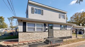 A two-story house with a stone foundation, a front porch, and a fenced yard. - Enjoyable 3-bedroom house with AC in St. Louis (St. Louis)