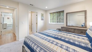 Um quarto com uma cama grande, cômoda, espelho e janela com persianas.