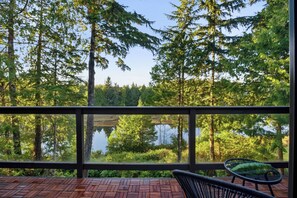 A wooden deck with a view of a forest and a lake. - Views of Spring Cove! • Rainforest Loft | Hyphocus Inn (Ucluelet)