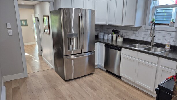 A modern kitchen with stainless steel appliances, white cabinetry, and a wooden floor. - Quidi Vidi Escape (St. John's)