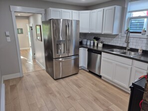 A modern kitchen with stainless steel appliances, white cabinetry, and a wooden floor. - Quidi Vidi Escape (St. John's)