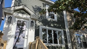 A two-story house with a front porch, a wooden staircase, and a mailbox. - Quidi Vidi Escape (St. John's)