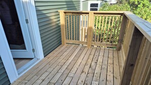 A wooden deck with a railing, a door, and a small shed in the background. - Quidi Vidi Escape (St. John's)