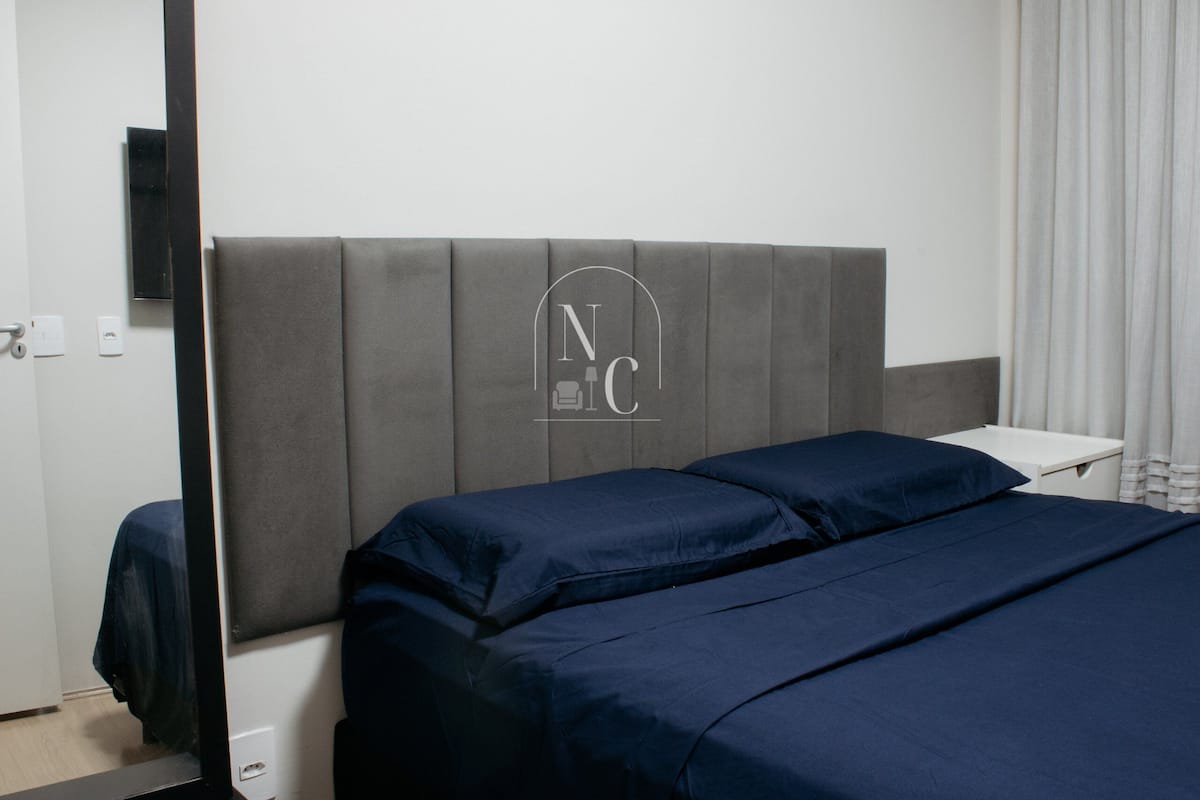 Une chambre d’hôtel avec un lit, une petite table de chevet, un téléviseur à écran plat fixé au mur et une fenêtre avec des rideaux.