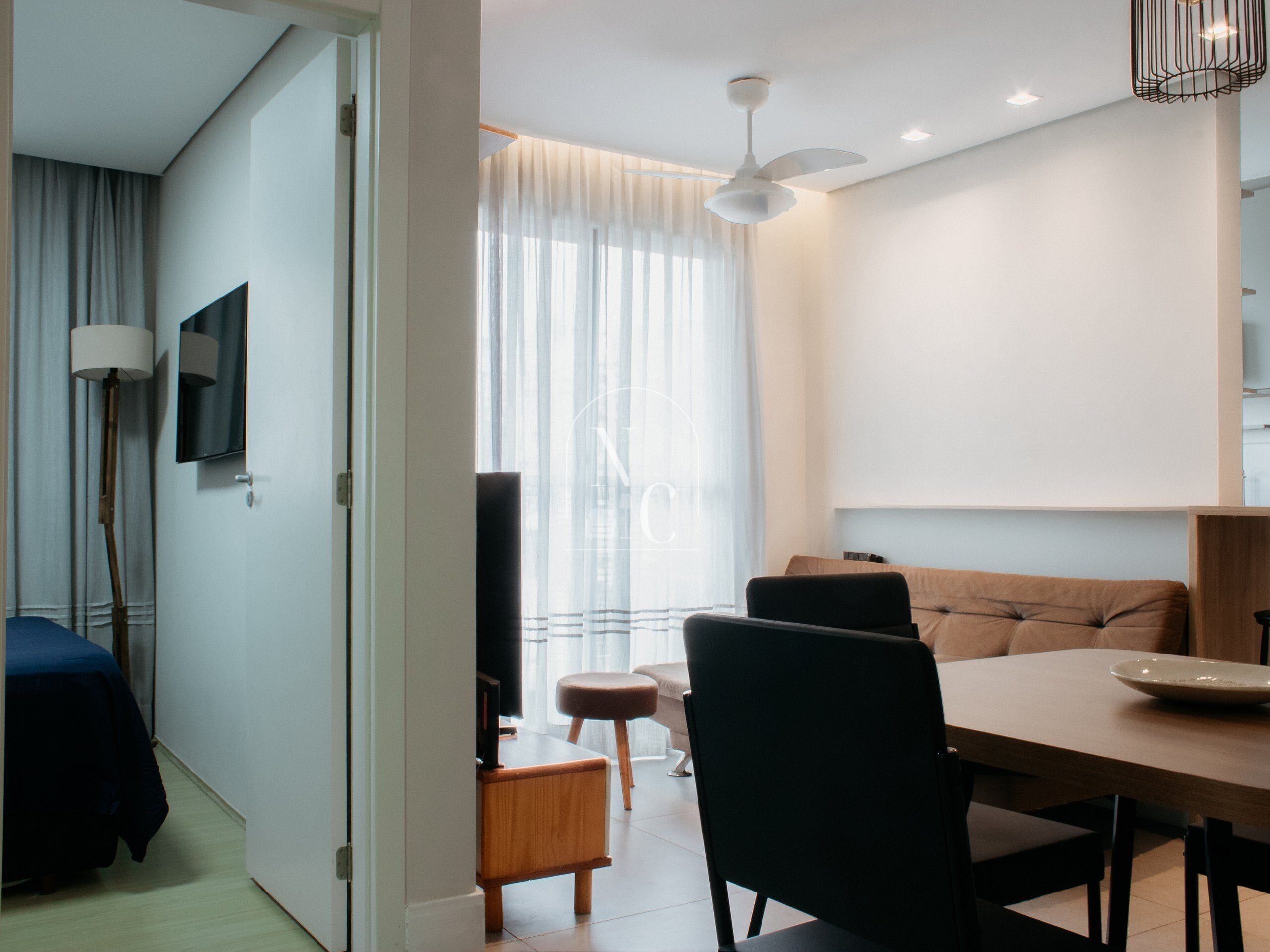 Una habitación de hotel moderna con comedor, sofá, televisor y ventilador de techo.