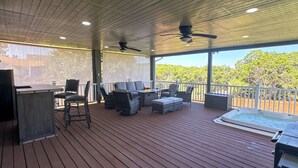A covered outdoor deck with wicker furniture, a hot tub, and ceiling fans. - Enjoyable 3-bedroom house with Jacuzzi, Mini Golf and Cantal AC in Canyon Lake. (Canyon Lake)