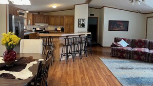 Une cuisine moderne avec des meubles en bois, un îlot central et un coin repas équipé de tabourets de bar.