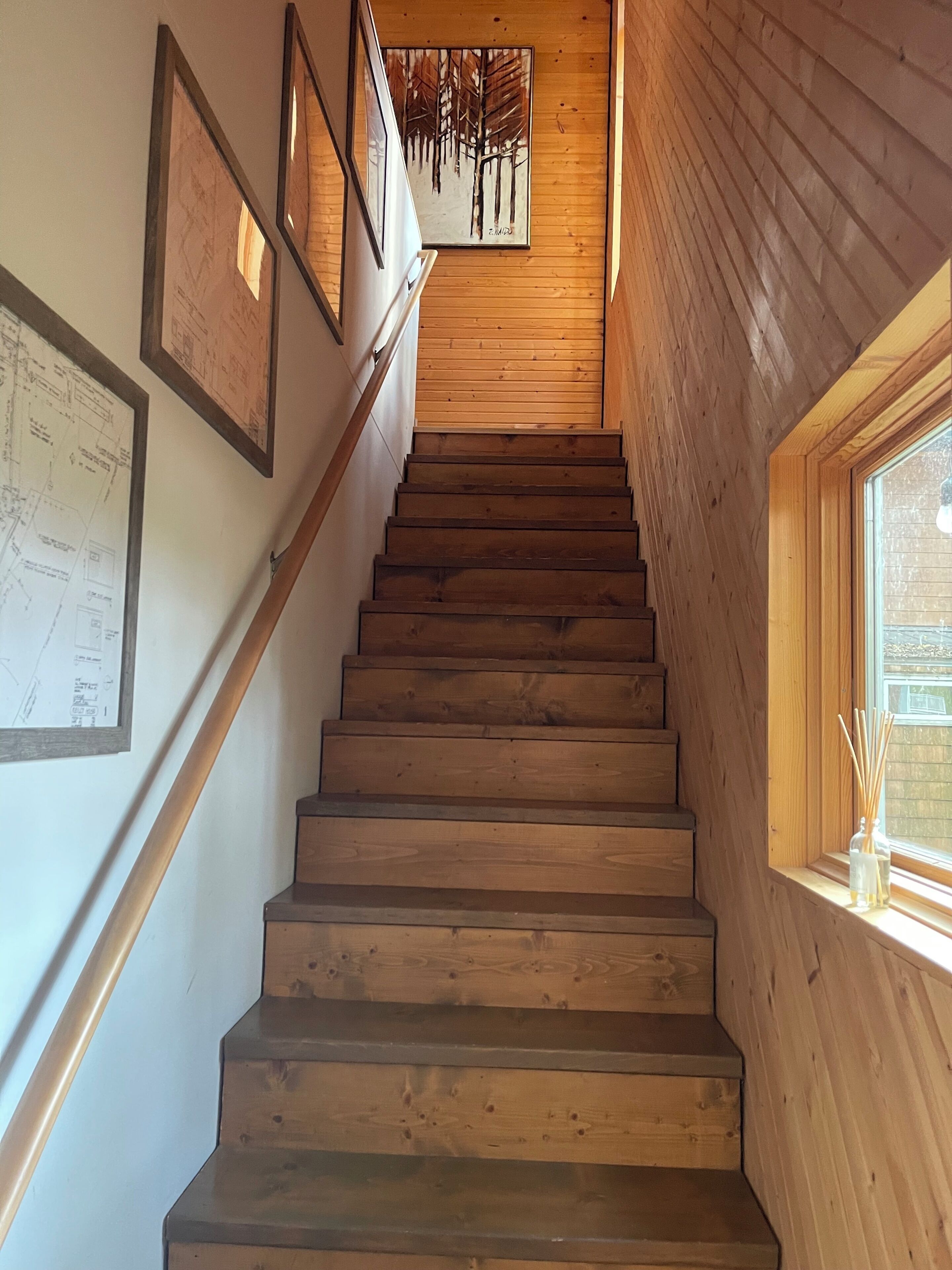 A wooden staircase with a wooden wall on one side and a window on the other.