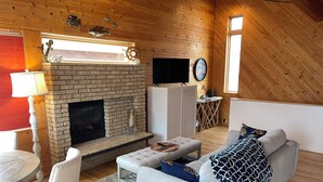 Una sala de estar acogedora con chimenea, televisor, sofá y comedor.