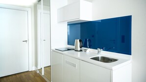 A modern kitchen with white cabinets, a stainless steel sink, and a blue backsplash. - Orbi City Panorama Sea View Studios (Batumi)