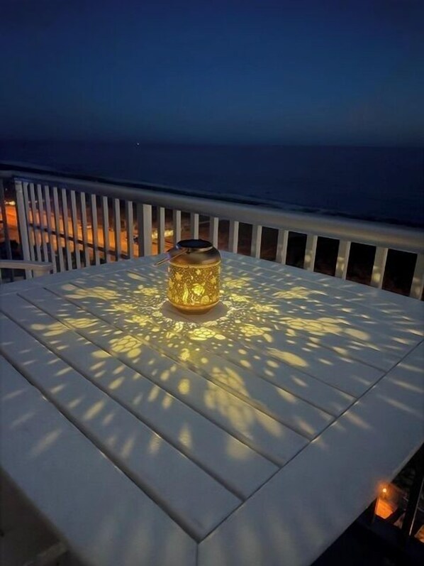 A white outdoor table with a decorative lantern in the center, surrounded by a railing. - Gulf-Front Luxury Condo on Pensacola Bch 2Bd/2Ba, Pool, Balcony (Pensacola Beach)