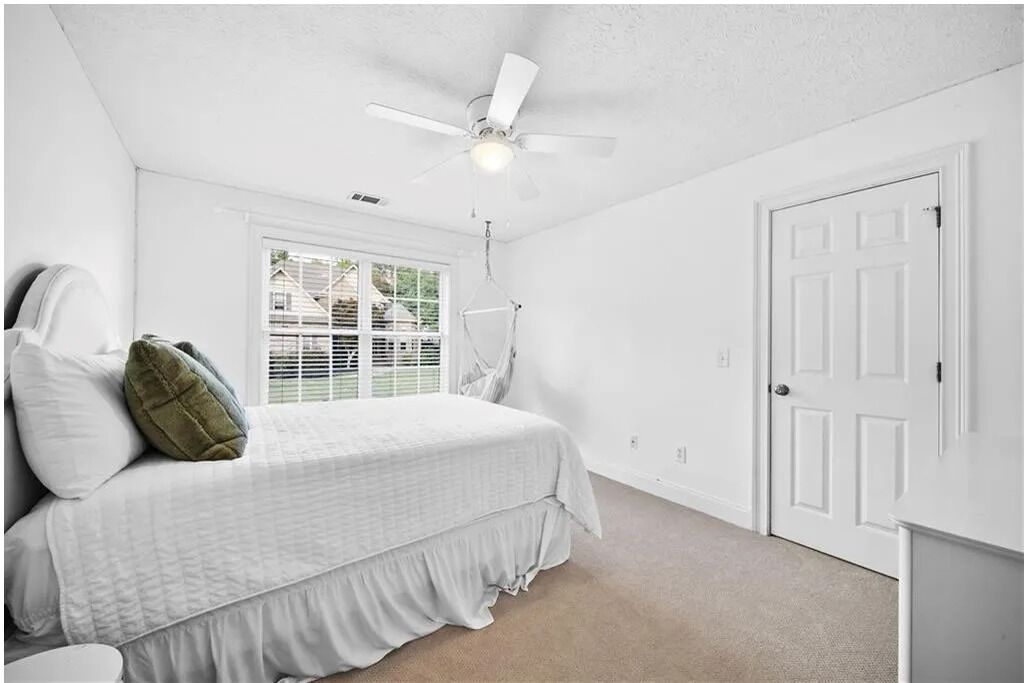 Quarto com cama, ventilador de teto, janela e porta.