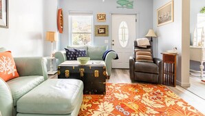 A living room with a light blue couch, a brown leather chair, a patterned rug, and a vintage suitcase as a coffee table. - Hammy on a Rye 2 Hammondsport NY (Hammondsport)