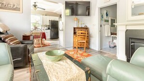 A living room with a sofa, a coffee table, and a fireplace. There is a dining area with a table and chairs. - Hammy on a Rye 2 Hammondsport NY (Hammondsport)