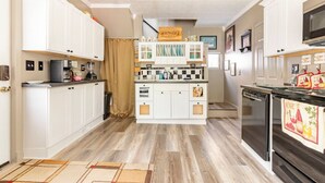 A compact kitchen with white cabinetry, a central island with a sink, and a microwave. - Hammy on a Rye 2 Hammondsport NY (Hammondsport)