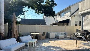 A backyard with a pool, outdoor furniture, and a covered patio area. - Spacious Long Beach home, steps to beach & train (Long Beach)