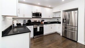 A modern kitchen with white cabinets, stainless steel appliances, and a black countertop.