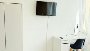 Une chambre à coucher moderne, équipée d’un lit, d’un bureau, d’une chaise et d’un téléviseur fixé au mur.