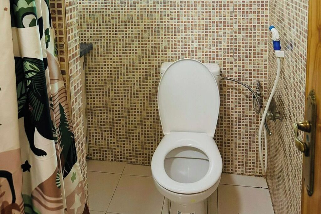 A bathroom with a white toilet, tiled walls, and a shower area.
