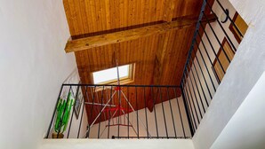 A wooden ceiling with a skylight, a metal railing, and a potted plant.