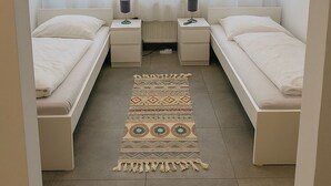 A bedroom with two single beds, a patterned rug, and a window with sheer curtains. - City apartment no. 6 with comfort (Pforzheim)