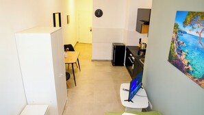 Una habitación de hotel con una cama, una mesita con una silla, un escritorio con una computadora y un cuadro en la pared.